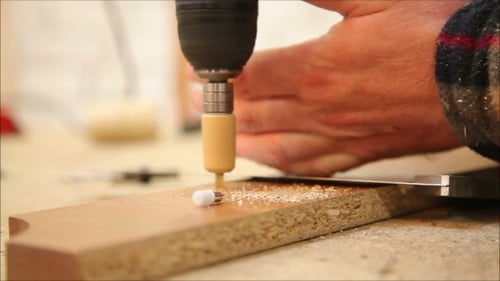 Man Drills Hole and Installs Fasteners into Plank