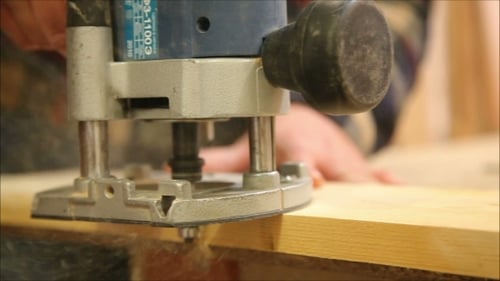 Craftsman Trims Wood with Router in Workshop