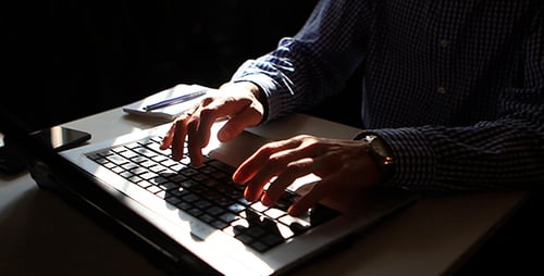 Adult Types on Laptop and Writes in Notebook