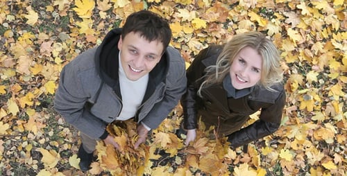 Couple Throws Autumn Leaves in Park from Above