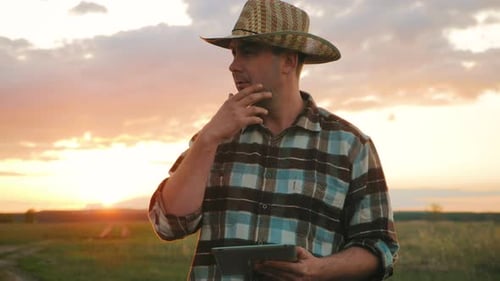 Farmer Using Tablet in Field at Sunset