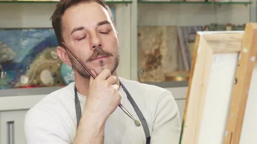 Man Painting Art on a Canvas in Studio