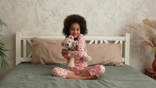 Smiling Girl Hugging Teddy Bear on Bed