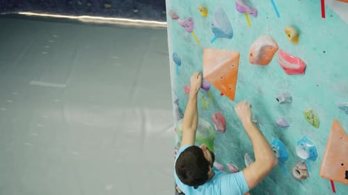 Slow Motion of Male Climber Pulling Himself Up on Climbing Wall in Sports Center
