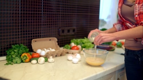 Woman Preparing Omelet in Kitchen with Fresh Ingredients