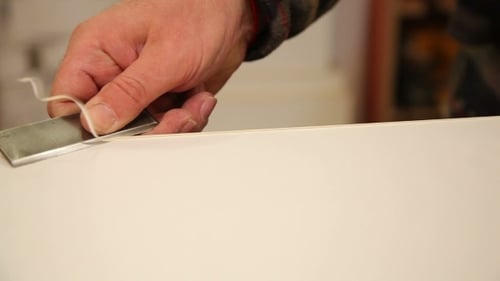 Man Cutting White Surface Edge