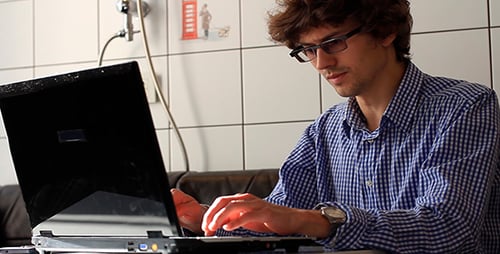 Young Adult Works on Laptop and Takes Call