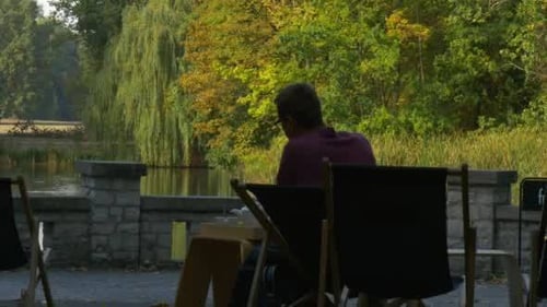 Person Relaxing at Lakeside Cafe Reading