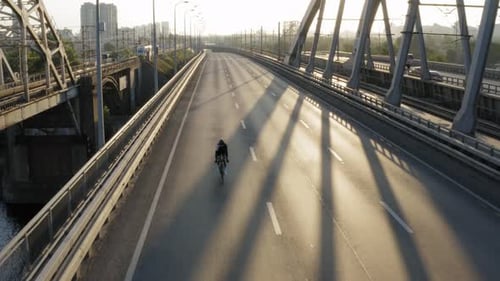 Aerial drone view of cyclist riding over the bridge