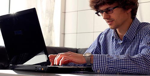 Young Adult Using Laptop and Talking on Phone