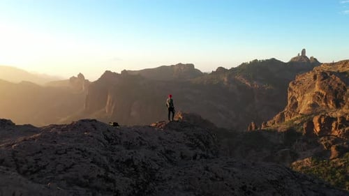 Man Watching Sun Setting Over Mountain Landscape