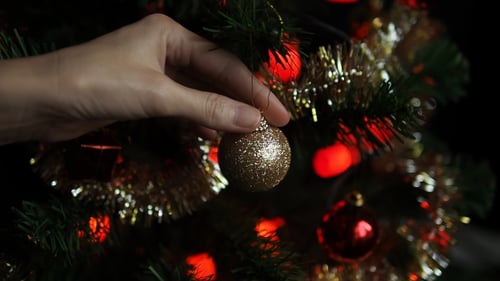 Hand Decorating Christmas Tree with Gold Ornament