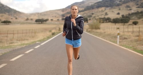 Garota fitness correndo na estrada nas montanhas