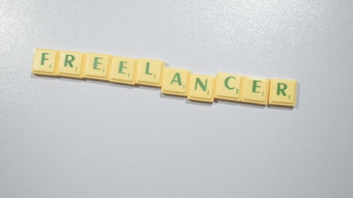 Hands Spell Freelancer with Letter Tiles on White