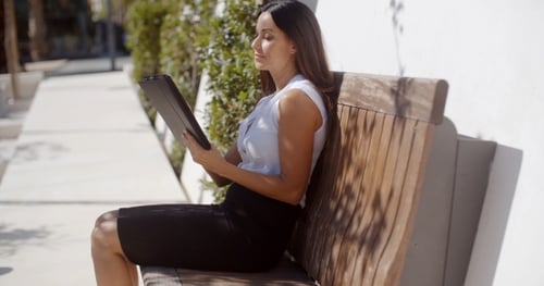 Businesswoman Using Tablet on Bench in City