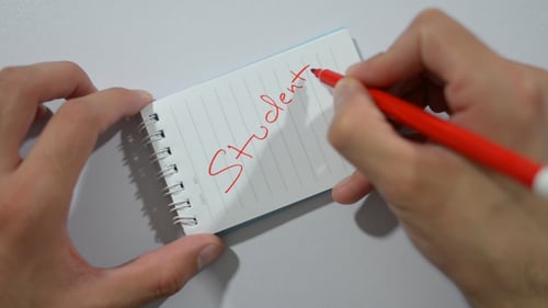Writing Student on Notepad with a Red Pen