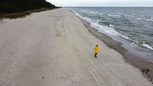 Lady is Going on the Sand Beach Alone the Stormy Ocean at Cold Windy Day Filmed By Drone