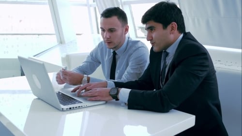 Businessmen Collaborating on Laptop in Bright Office