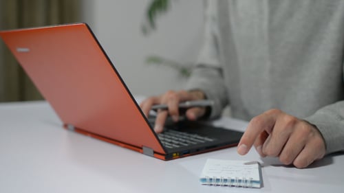 Adult Working on Orange Laptop in Office