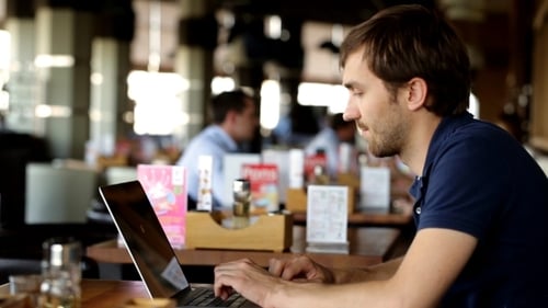 Junger Geschäftsmann benutzt am Laptop im Café