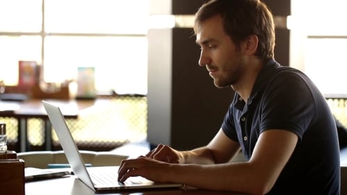a Man Sitting In a Cafe And Working At a Laptop