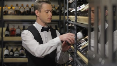 Man Selecting Wine Bottle from Shelves in Liquor Store