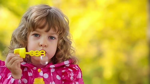 Child Blowing Bubbles in a Natural Outdoor Setting