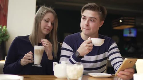 Young Adults Drinking Coffee in Cafe Using Technology