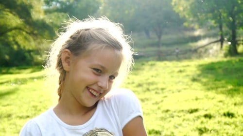 Smiling Girl Posing Outdoors in Sunny Meadow