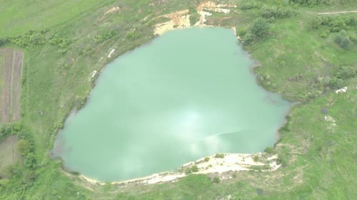 Green water surface of lake with reflections of cloudy sky 4K aerial footage