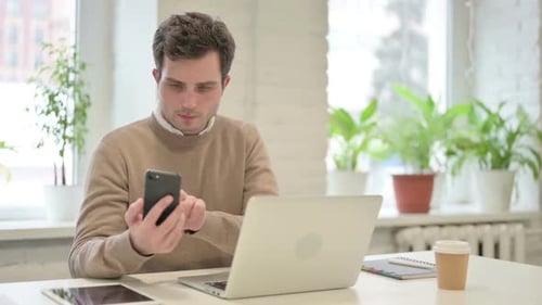 Man Using Smartphone While Using Laptop in Office