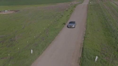Car Driving On The Dirt Road Among Windmills