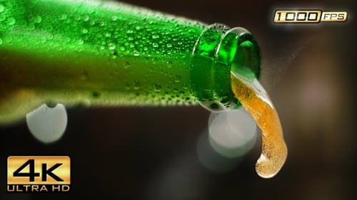 Refreshing drink pouring from a green glass bottle