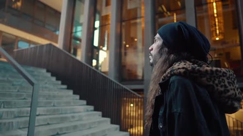 Portrait of Long Haired Hipster Walking on Street in Modern City