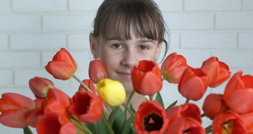 Smiling Child Holding a Tulip Flower Bouquet Indoors