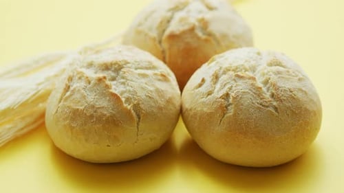 Bread Rolls with Wheat on Yellow Background