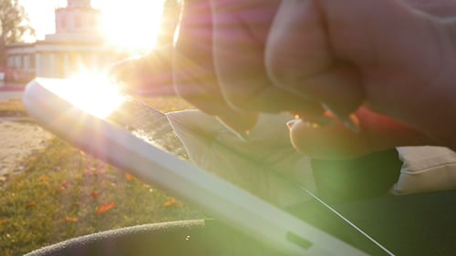 Frau benutzt ihr Touchpad bei Sonnenuntergang