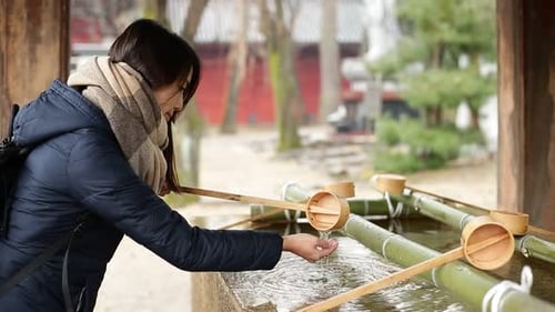 Woman washing with water purification in front of Japanese Temple