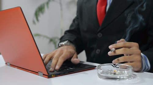 Homme fumant et travaillant sur ordinateur portable
