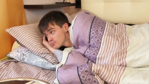 Young Man Waking Up In Bedroom