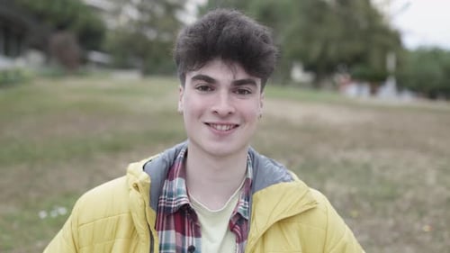 Young Man Smiling Outdoors Wearing Yellow Puffer Jacket