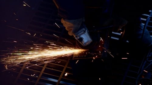 Worker Cutting Metal in Dark with Sparks