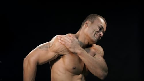 Muscular Man Touches Shoulder in Pain