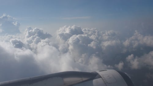 Airplane Flying Above Fluffy White Clouds in Sky