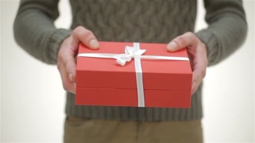 Hands Holding Red Gift Box with White Ribbon