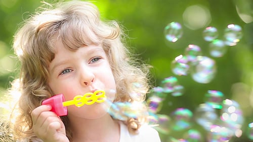Child Blowing Bubbles in a Sunny Green Park