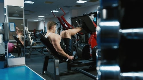 Man Works Out on Leg Press Machine at Gym