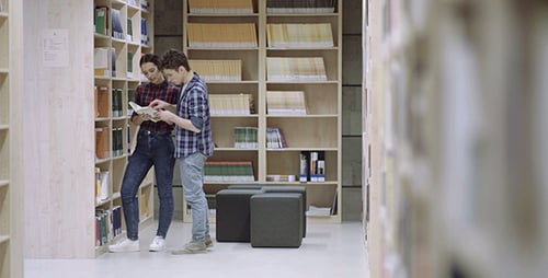 Students Studying a Book Together in a Library
