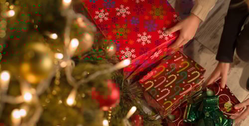 Arranging Christmas Gifts near Decorated Christmas Tree