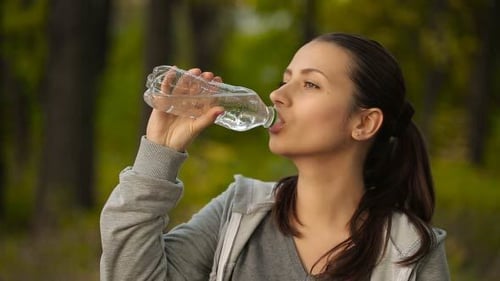 Brunette Woman Drinks Water Outdoors